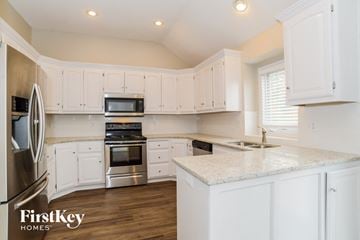 Kansas City house for rent - A kitchen with white cabinets and a marble countertop.