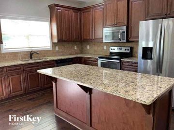 Clermont house for rent - a kitchen with wooden cabinets and a granite counter top