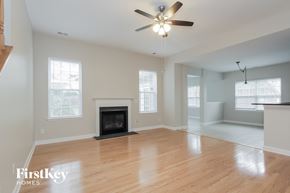 Mooresville house for rent - an empty living room with a fireplace and a ceiling fan