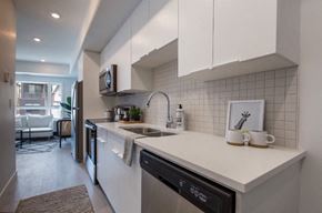 Winnipeg apartment for rent - A modern kitchen with white cabinets and a black dishwasher.