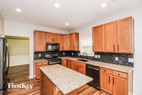 Lithia Springs house for rent - a kitchen with wooden cabinets and granite counter tops and black appliances
