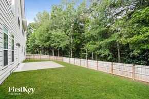 Lithia Springs house for rent - a backyard with a fence and green grass and trees