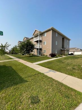 Fargo apartment for rent - a sidewalk leading to an apartment building on a green lawn