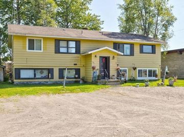Kenai apartment for rent - a yellow house with a yard and a gravel driveway