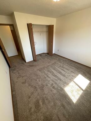 Fargo apartment for rent - an empty living room with carpet and a door to a closet