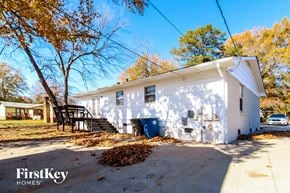 Winston Salem house for rent - a white house with a black staircase and a yard with trees