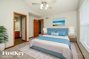 Westerville house for rent - A bedroom with a bed, a ceiling fan, and a painting of a beach scene on the wall.