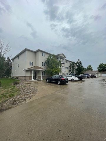 Fargo apartment for rent - a parking lot with cars in front of a building