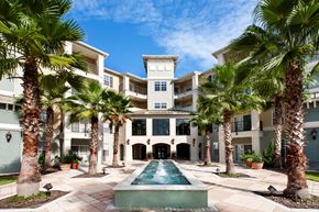Orlando apartment for rent - A large house with a pool surrounded by palm trees.