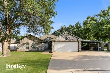 Burleson house for rent - a stone house with a garage and a tree