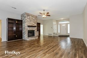 Burleson house for rent - an empty living room with a stone fireplace and wooden floors