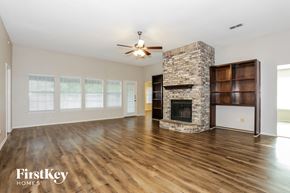 Burleson house for rent - a living room with a stone fireplace and wooden floors