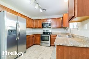 Tolleson house for rent - a kitchen with wooden cabinets and stainless steel appliances