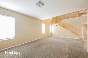 Surprise house for rent - A spacious room with a carpeted floor and a staircase with a wooden railing.