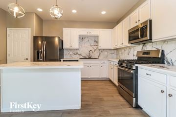 Buckeye house for rent - a kitchen with white cabinets and stainless steel appliances and marble counter tops