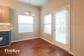 Bacliff house for rent - an empty dining room with wood flooring and a door to the kitchen