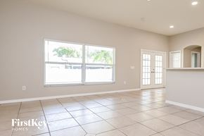 Valrico house for rent - an empty living room with large windows and tiled flooring