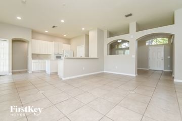 Valrico house for rent - an open kitchen and living room with white cabinets and tiled floors
