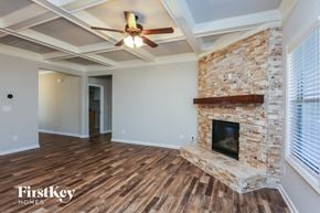 Gainesville house for rent - A room with a stone fireplace and a ceiling fan.