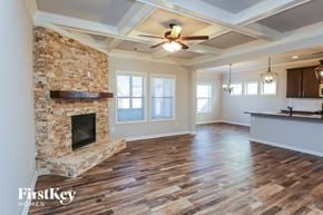 Gainesville house for rent - A spacious room with a stone fireplace and wooden flooring.