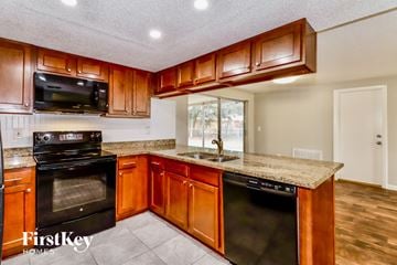 Port Richey house for rent - a kitchen with wooden cabinets and black appliances and granite counter tops