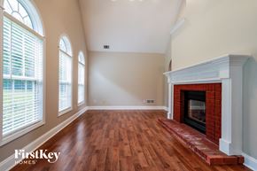 Loganville house for rent - an empty living room with a brick fireplace and wooden floors