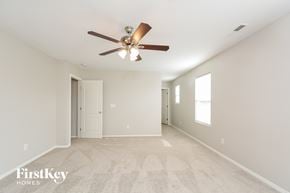 Durham house for rent - A spacious room with a ceiling fan and beige carpeting.
