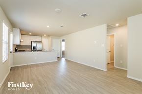 Converse house for rent - A spacious, empty room with wooden floors and white walls, with a kitchen area visible in the background.