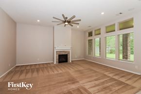 Humble house for rent - an empty living room with a fireplace and a ceiling fan
