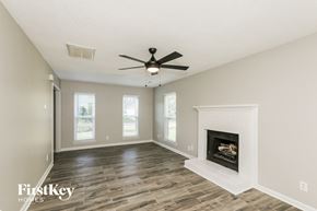 Charlotte house for rent - A spacious room with a fireplace and a ceiling fan.