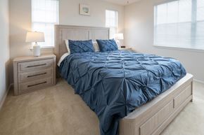 Columbus apartment for rent - A bed with a blue comforter and matching pillow cases sits in a bedroom with a nightstand and two lamps.