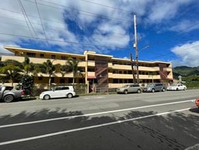 Honolulu apartment for rent - A white car is parked in front of a yellow building.