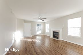 Waxhaw house for rent - A spacious room with a fireplace and a ceiling fan.
