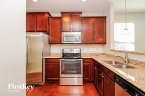 Winston-Salem house for rent - a kitchen with wooden cabinets and stainless steel appliances and granite counter tops