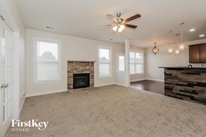 Mooresville house for rent - an empty living room with a fireplace and a ceiling fan