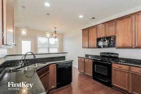 Mooresville house for rent - a kitchen with wooden cabinets and black counter tops and a sink