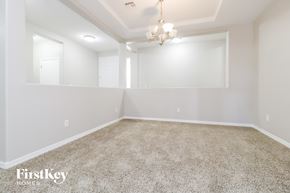 Buckeye house for rent - A spacious room with a carpeted floor and a chandelier hanging from the ceiling.
