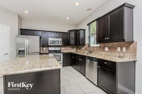 Saint Cloud house for rent - a kitchen with black cabinets and granite counter tops and stainless steel appliances