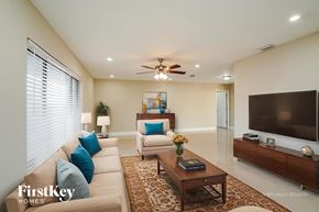 Cape Coral house for rent - A living room with a beige couch, a coffee table, and a flat screen TV mounted on the wall.