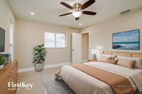 Cape Coral house for rent - A bedroom with a bed, a ceiling fan, and a painting of a beach scene on the wall.