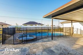 Cape Coral house for rent - A swimming pool with a black fence and a house in the background.