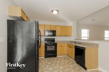 Charlotte house for rent - a kitchen with wood cabinets and black appliances and a refrigerator