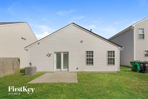 Charlotte house for rent - the exterior of a white house with a grassy yard and a driveway