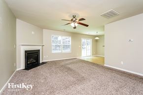 Kernersville house for rent - A spacious living room with a fireplace and a ceiling fan.
