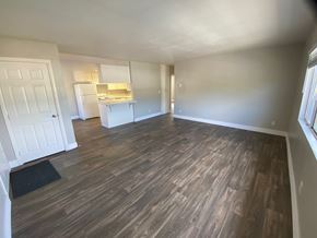Vista apartment for rent - an empty living room with wooden floors and a kitchen