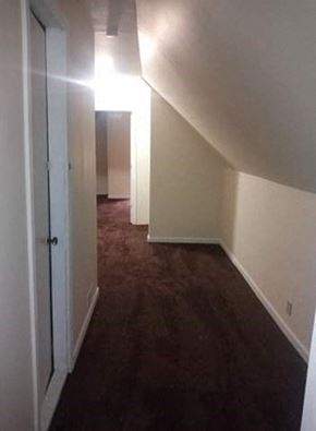 Cleveland apartment for rent - A hallway with a white door on the left and a brown carpet.