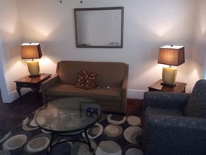 Cleveland apartment for rent - A living room with a couch, two lamps, a coffee table, and a mirror.