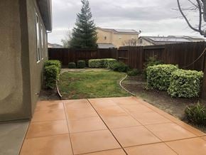 Manteca house for rent - a backyard with a tiled patio and a yard with grass and a fence