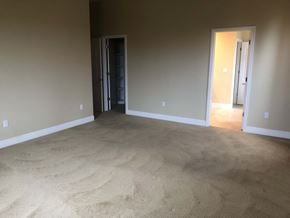 Manteca house for rent - a empty living room with carpet and a door to a hallway