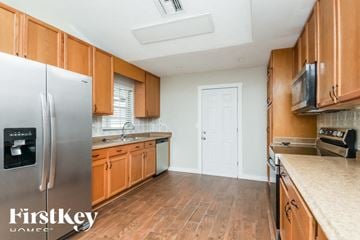Saint Cloud house for rent - a kitchen with wooden cabinets and a stainless steel refrigerator